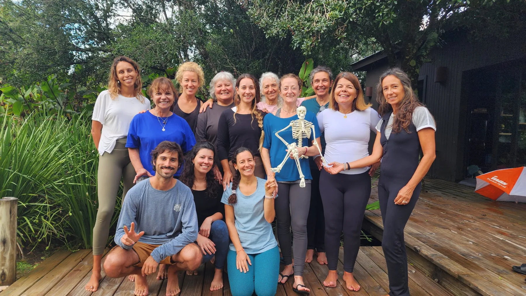 Grupo de un retiro anterior de Portal, sonriendo en el deck de madera rodeado de plantas