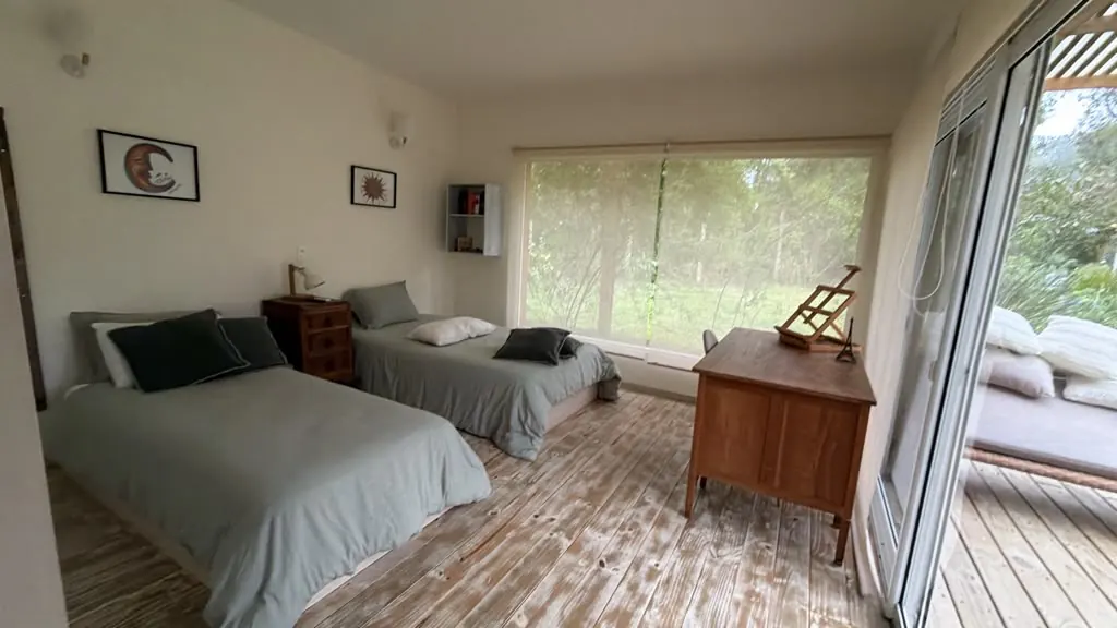 Habitación compartida con camas individuales y ventanal al bosque