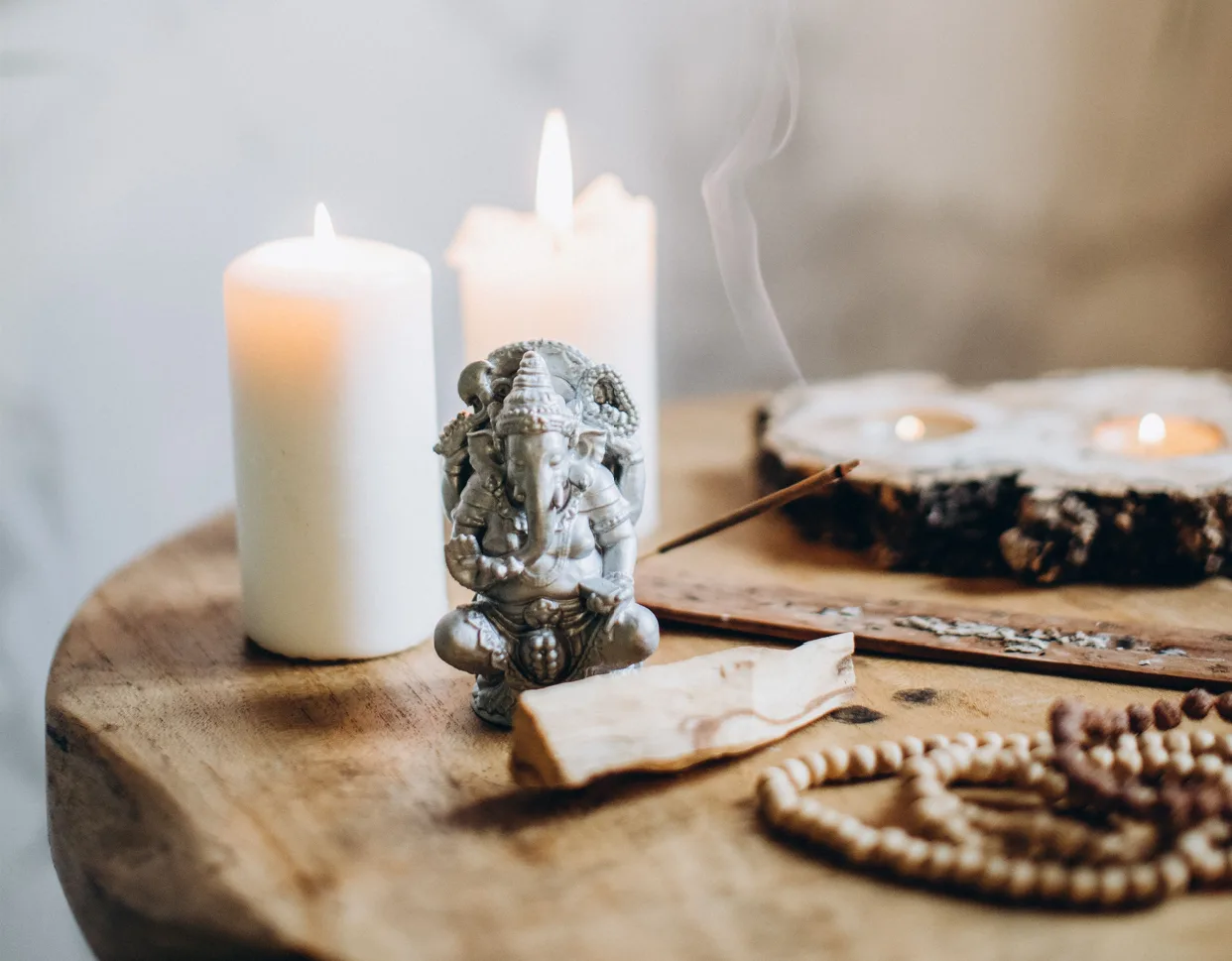 Altar con velas encendidas, Ganesha, palo santo, incienso y un mala de cuentas