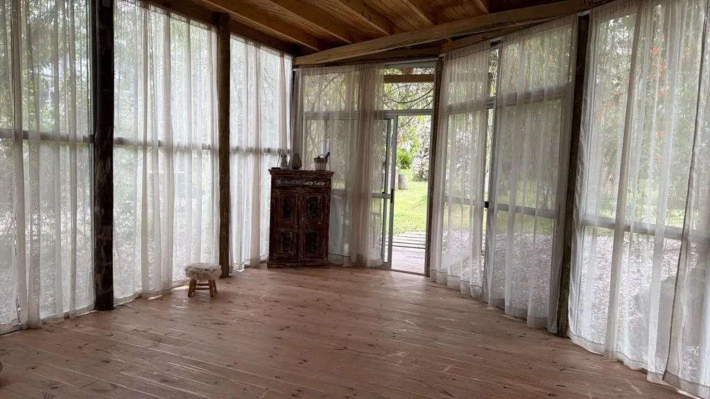 La sala de práctica, con piso de madera y cortinas blancas abiertas al jardín